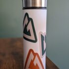 All 3 stickers in orange, green, and tan stuck on a thermos